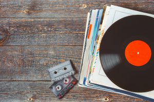 A stack of old vinyl records and cassette tapes are on the board