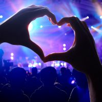 Crowd of Audience at during a concert with a heart shaped hands shadow